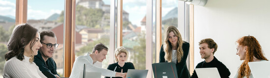 Sieben Personen arbeiten versammelt um einen Tisch an ihren Laptops und besprechen Dinge miteinander. | © FH Kufstein Tirol