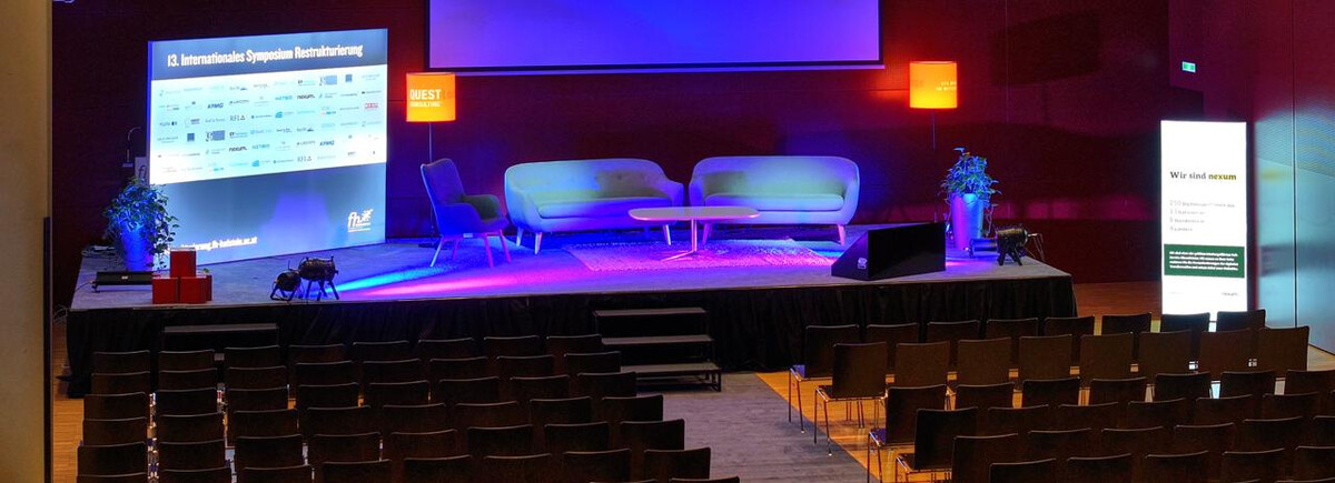 Leerer Konferenzsaal mit Bühne, moderner Möblierung und Präsentationsbildschirm, vorbereitet für die Jahreskonferenz 2024. | © FH Kufstein Tirol