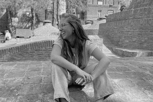 Elena lachend, sitzt auf einem Steinfussboden